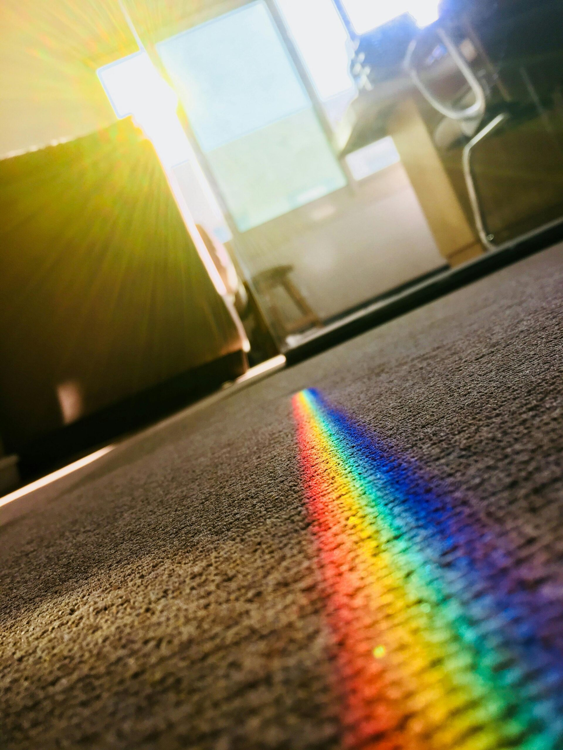 A vibrant rainbow reflection on a carpet, created by sunlight passing through crystal glass, adds color to a modern room.